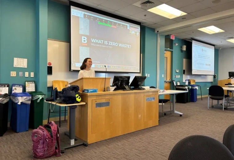 A woman stands behind a podium in front of a classroom