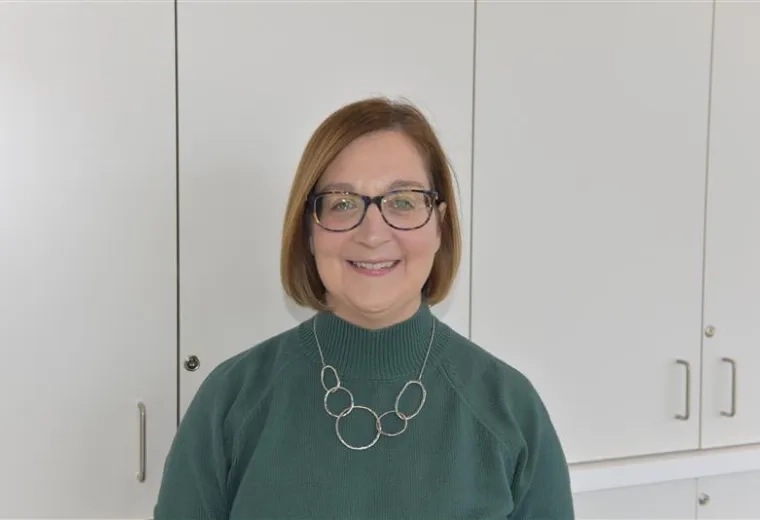 kathryn wears a moss colored top and silver looped necklace