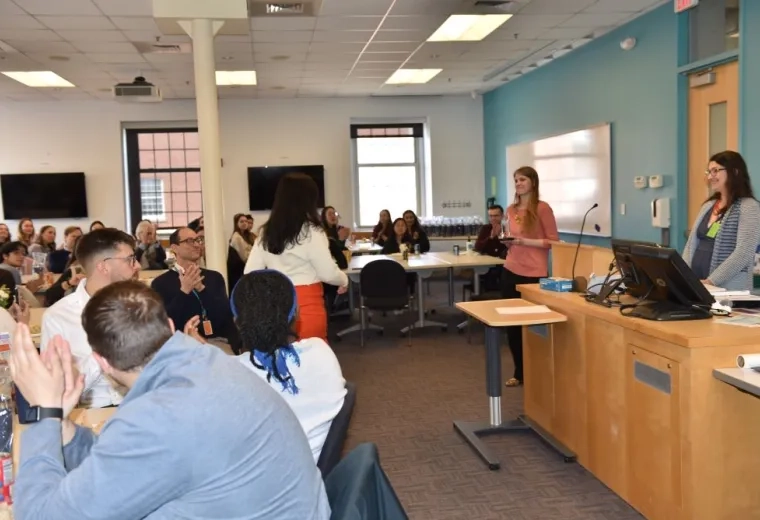 People sitting at tables watch a person go to accept an award