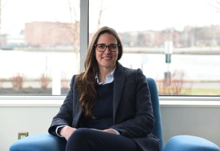 A woman sits in a chair in front of a window