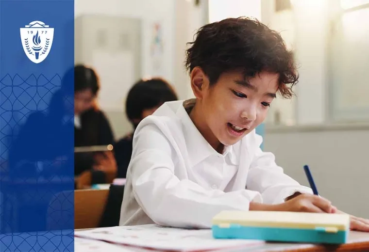 Kid with black hair sitting at desk in school