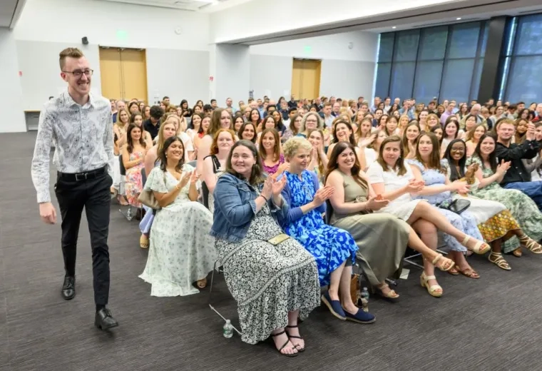 A man walks forward while people in the audience clap
