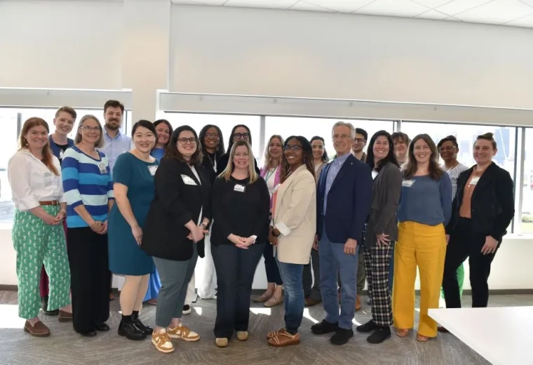 A group of people pose in front of windows