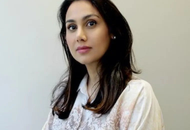 Reem Alansari has long dark brown hair and is wearing a white and blue top.