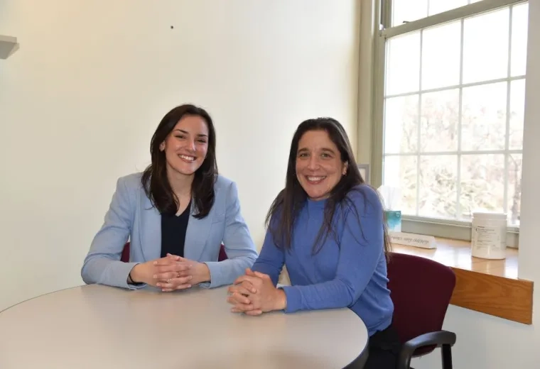 Two women sitting next to each other at a round table