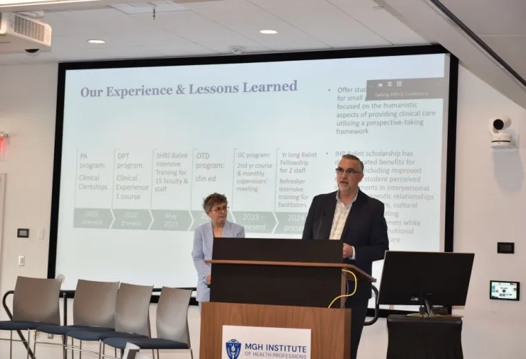 A man stands at the podium while a woman looks on from the stage