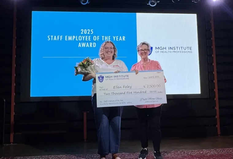 A photo of two women on a stage holding a check.