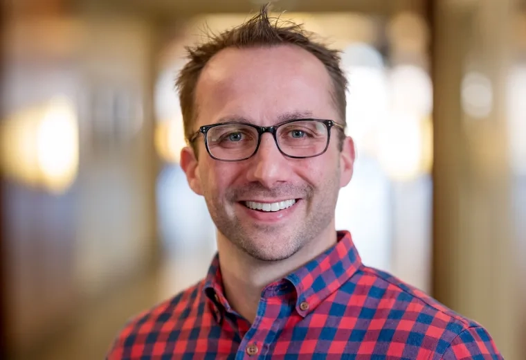 Christopher Joyce has short hair, is wearing glasses, and a red and blue checkered shirt
