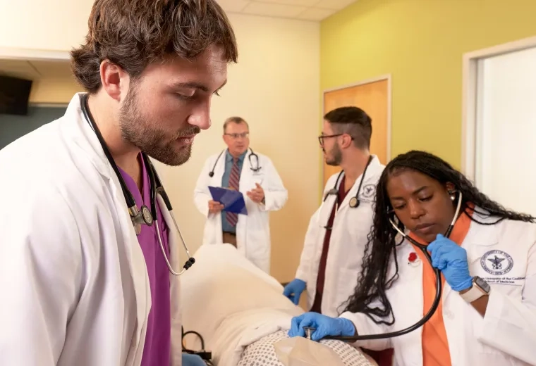 a woman uses a stethoscope on a manikin