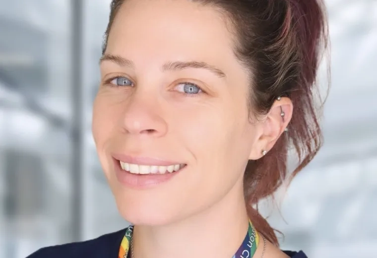 Brenna has a high ponytail and a rainbow lanyard around her neck