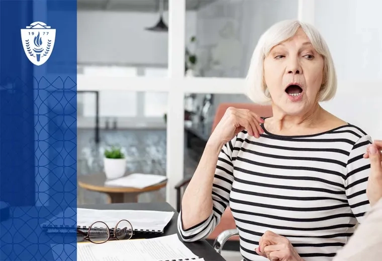Older woman with white hair sitting at a table working with a speech language pathologist