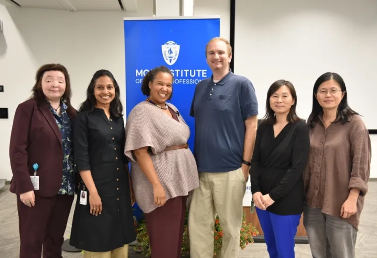 Six people stand in front of a banner that says MGH Institute