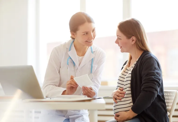 pregnant woman chats with a woman in a lab coat