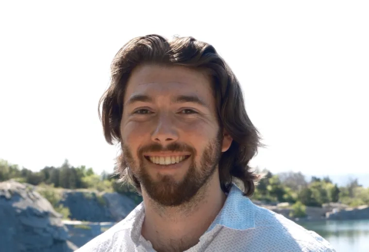 Jaryd Sullivan has shoulder length brown hair, a short beard, and is wearing a white button down.