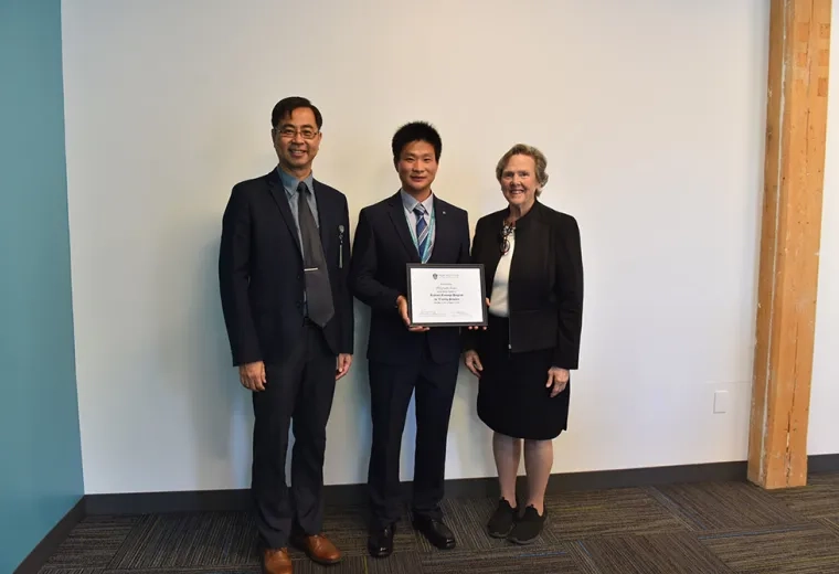 Three people pose against a white wall