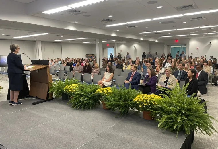woman at a podium speaking to a mixed crowd