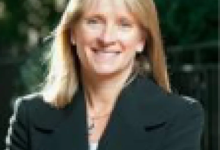 Headshot of woman with long blonde hair smiling and looking at the camera, and wearing a black jacket