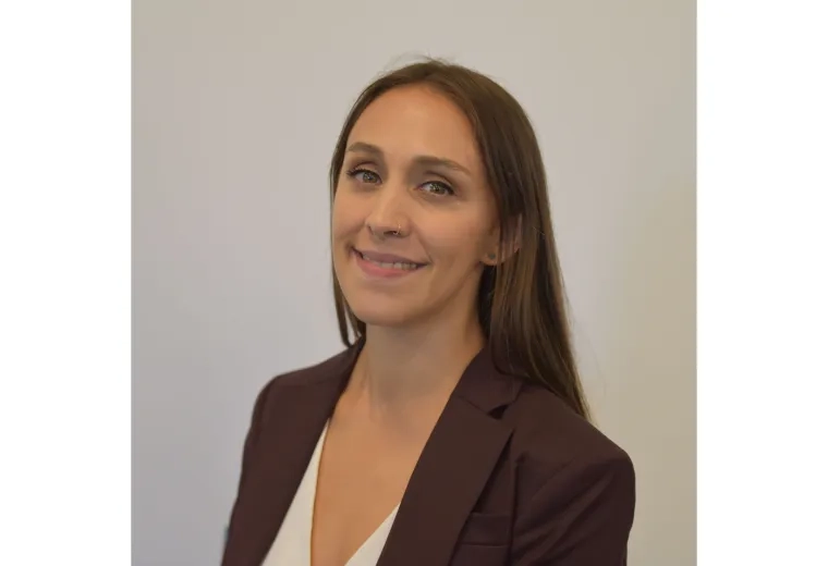 Headshot of Woman with long dark hair wearing white shirt and black jacket against a white background