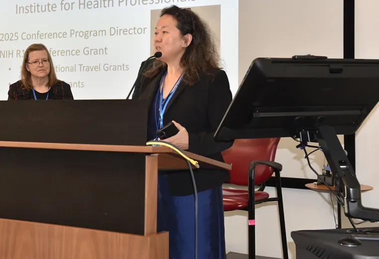 Woman stands podium, speaking into microphone
