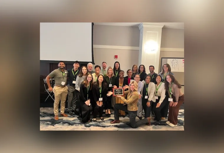 A group of people with one person in front holding a plaque