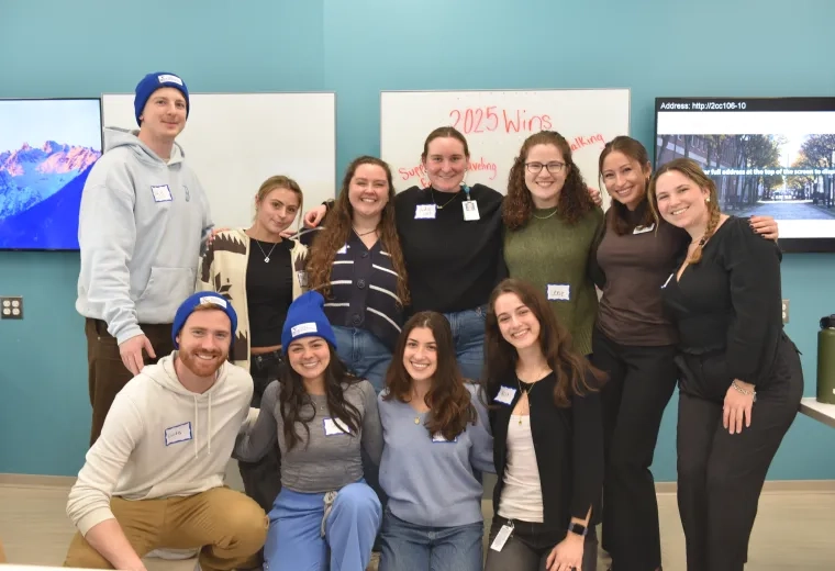 Eleven people pose in front of a board that says 2025 wins