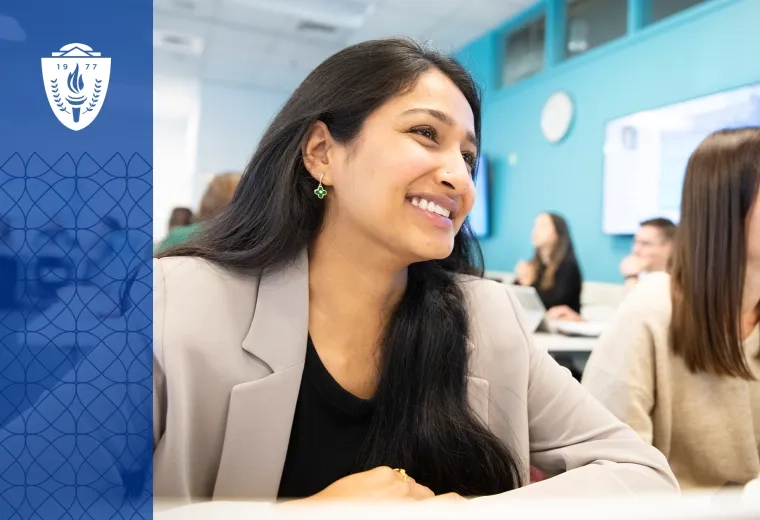 Two women sitting in at a classroom desk and smiling