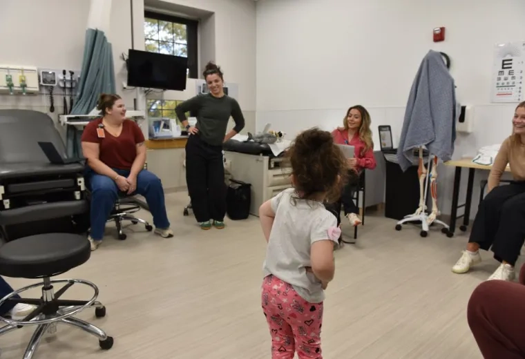 Small child with hands on hips in front of 4 women 