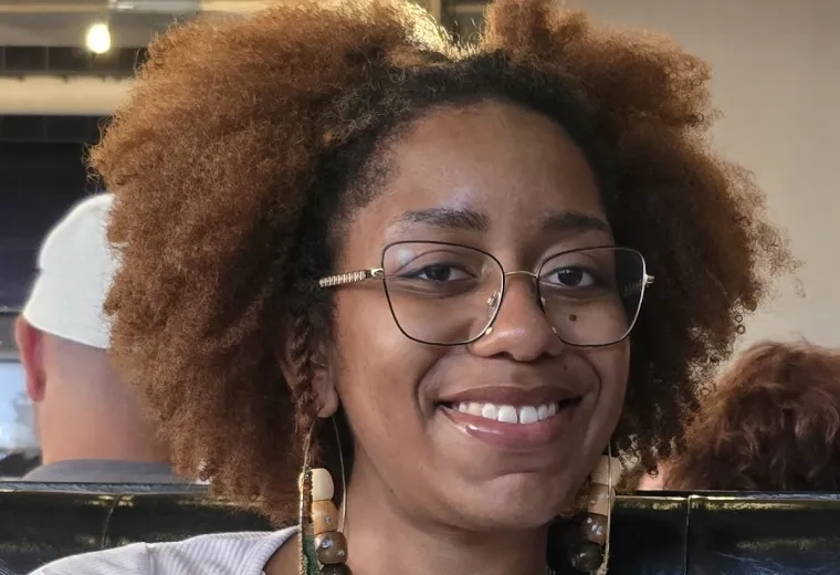Headshot of woman with frizzy brown hair wearing glasses and long earings