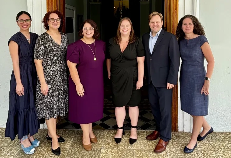 Six people post in front of a doorway