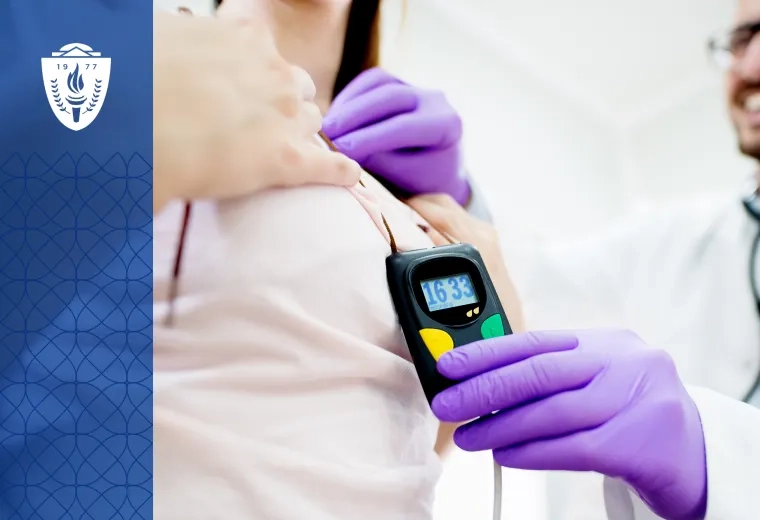 Doctor wearing lab coat and purple gloves holding a small rectangular medical device up to patient.