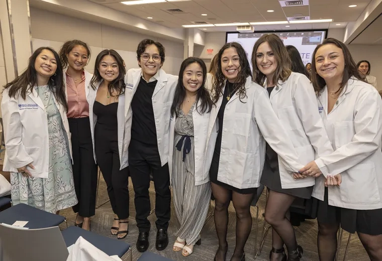 Eight people wearing white coats pose for a photo. 
