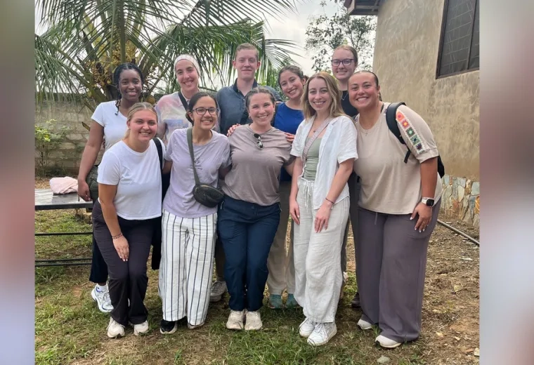Ten people stand in two rows to pose for photo