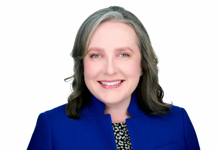 Headshot of Woman against a white background wearing a blue jacket 