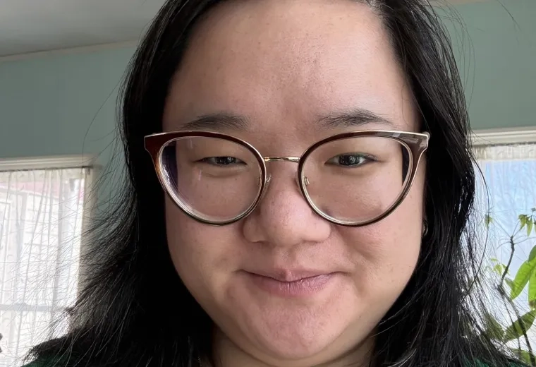 Headshot of woman with long black hair wearing glasses and a green shirt