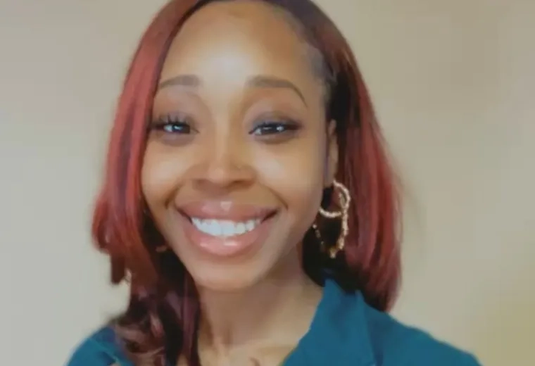 Headshot of a woman with dyed red hair smiling at the camera and wearing a blue shirt
