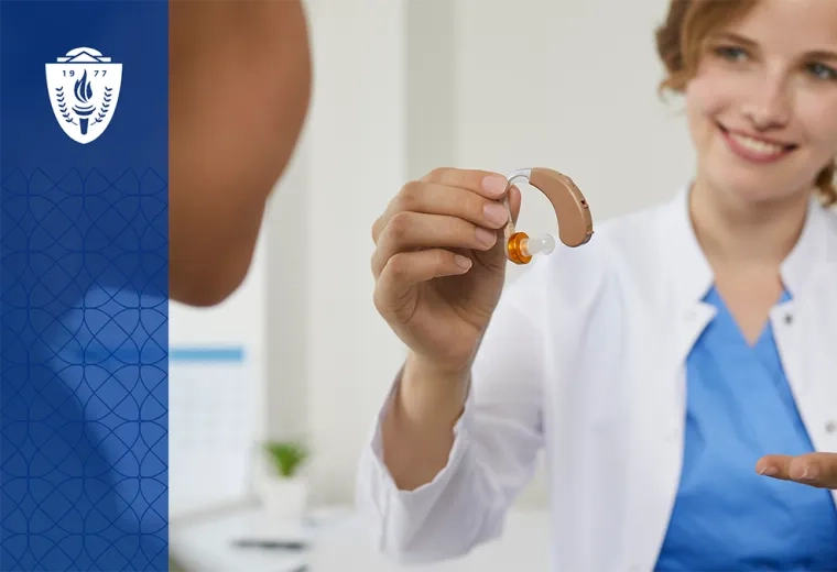 Woman wearing white lab coat holding a hearing air