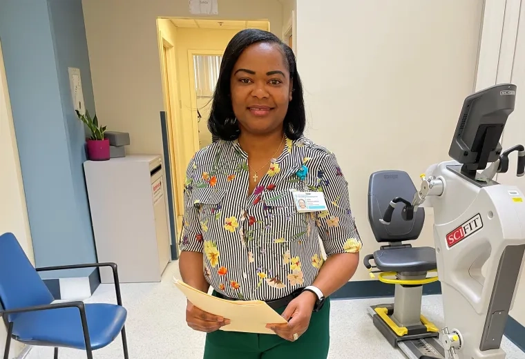 woman with manila folder standing in front of an exercise bike