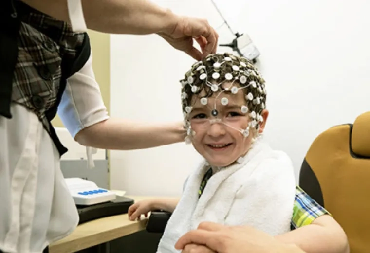 child smiling with head node cap on