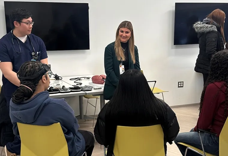 Two people stand in front of three people sitting in chairs