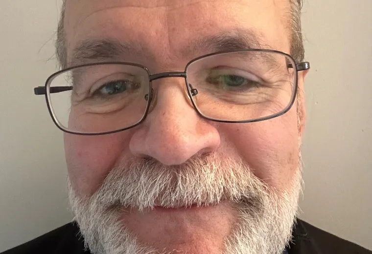 Headshot of man white white beard and mustache wearing glasses against a white background