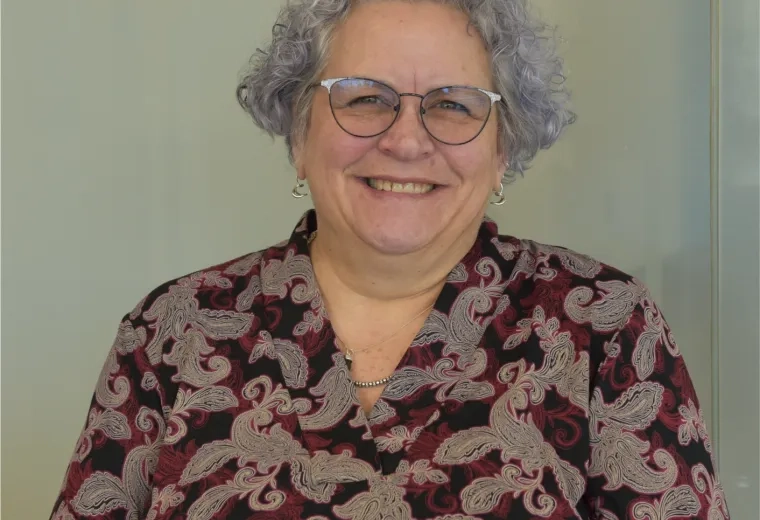 Karen has black framed glasses and grey wavy hair 