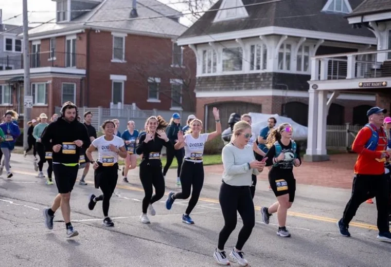 People running a race with two women in the center raising their hands