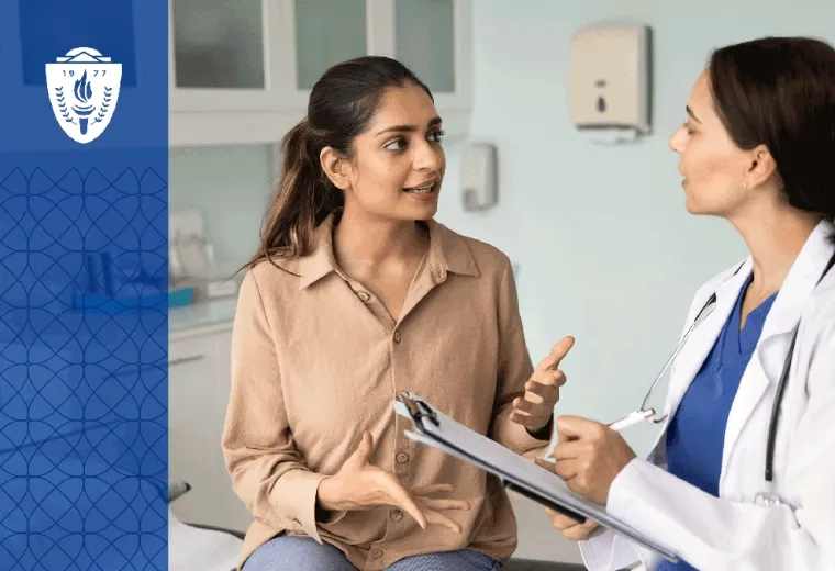a Women's Health Nurse Practitioner in a white lab coat makes a note as a woman sitting on an exam table talks