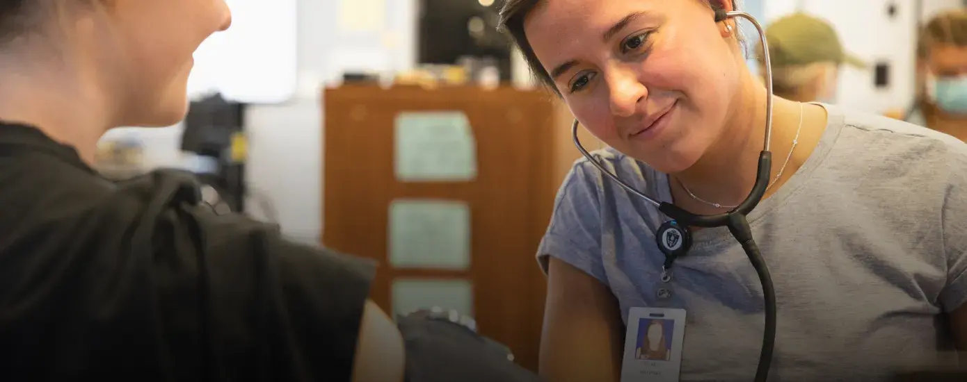 Student using a stethoscope to listen to the pulse of another individual.  