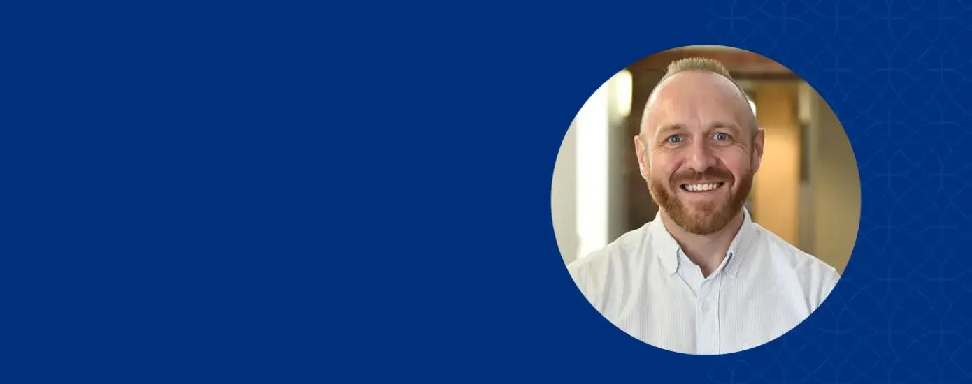 brad has a reddish brown beard and mustache and wears a white collared shirt