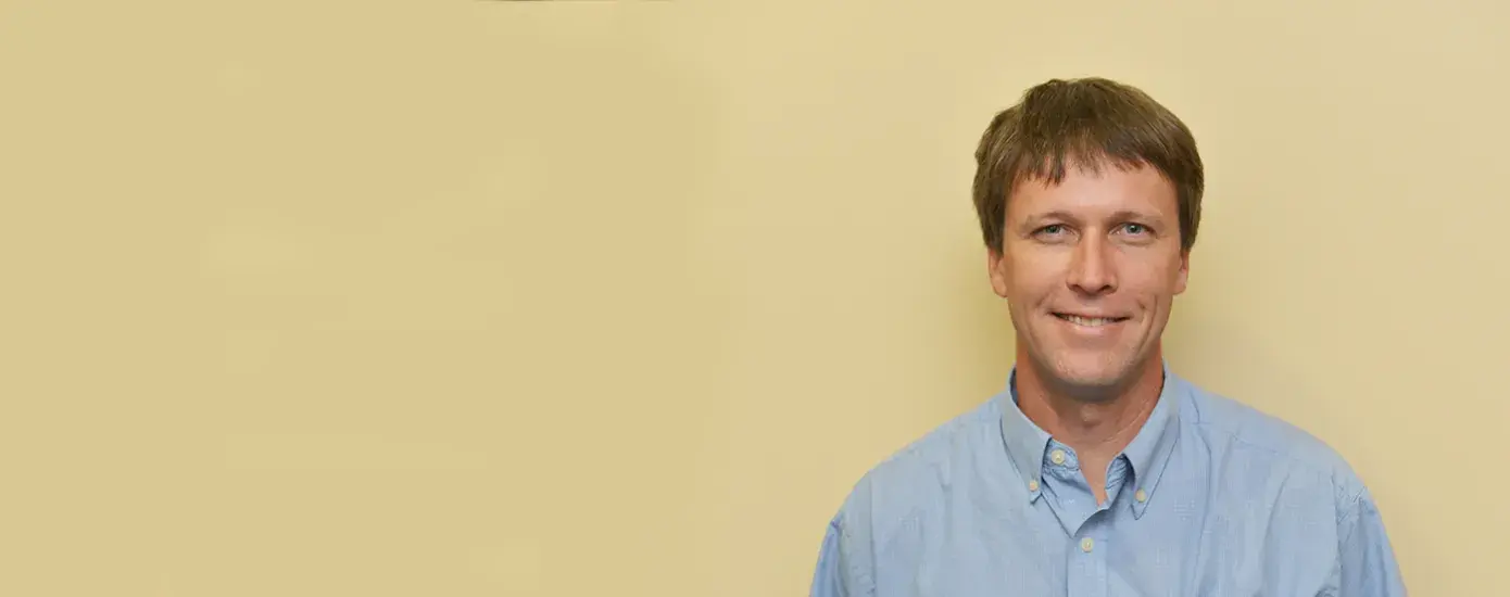 jason wears a blue collared shirt and a smile