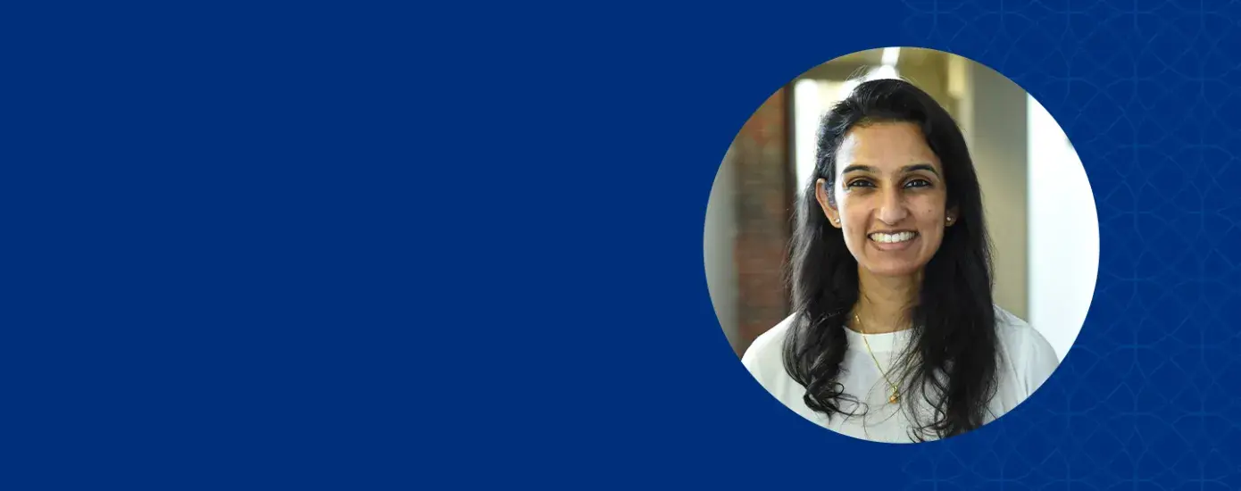 isha has shoulder length black hair and is wearing a gold chain and a cream long sleeve top