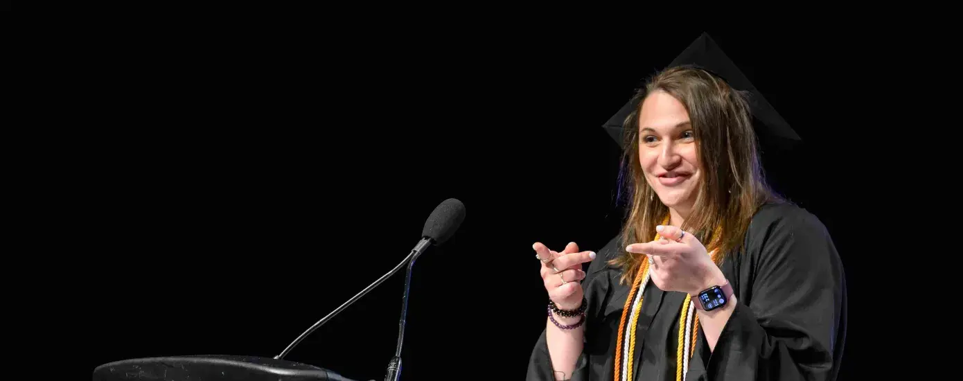 Woman in cap and gown talking at podium