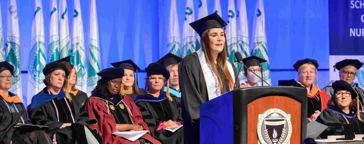 Woman in cap and gown talking at podium