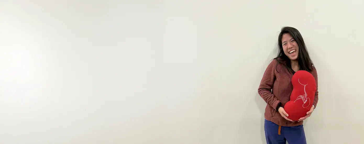 woman holds a kidney shaped pillow